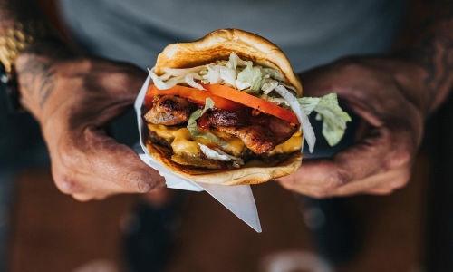 Bustling community with plenty of dining choices person holds a thick, juicy burger with both hands